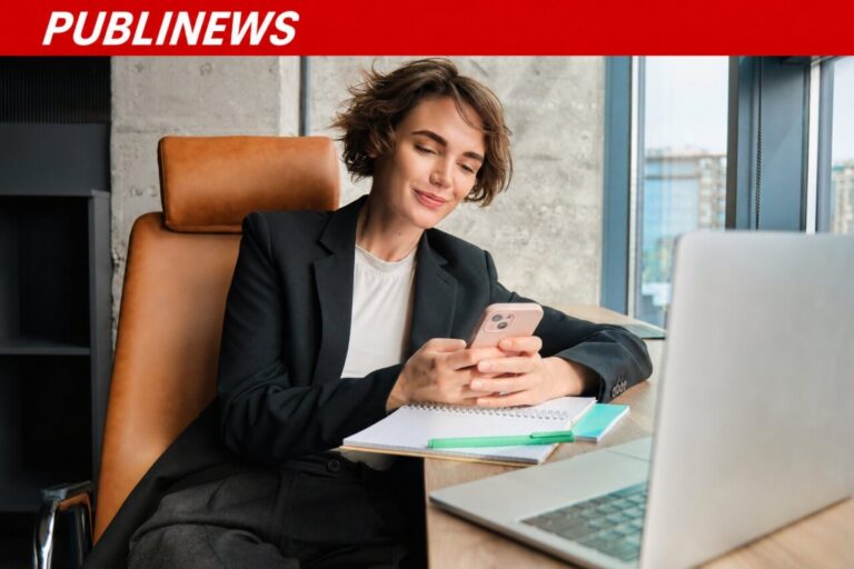 Mujer revisando su teléfono móvil en una oficina moderna.