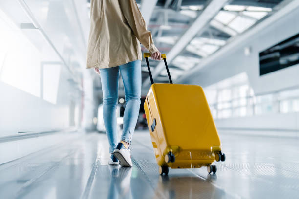 Persona caminando con maleta amarilla en un aeropuerto moderno